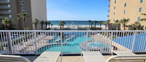 A pool area with multiple swimming pools, lounge chairs, and a view of the beach and ocean.