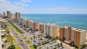 Un hotel costero con varios edificios altos, un estacionamiento y vistas al océano.