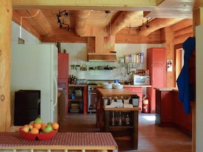 A rustic kitchen with wooden beams, a central island, and various kitchen appliances.