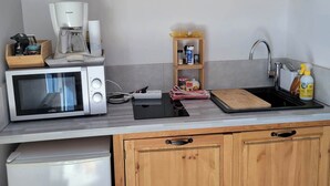 A compact kitchen with wooden cabinets, a microwave, a coffee maker, and a small sink. - Gite les marmottes with private spa (GERARDMER)