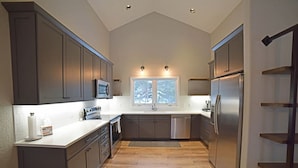 A modern kitchen with dark cabinets, stainless steel appliances, and a large window providing natural light. - Spacious and Scenic Mountain Home (Silverthorne)