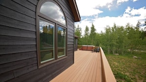 A wooden deck with a hot tub and chairs, surrounded by trees. - Spacious and Scenic Mountain Home (Silverthorne)