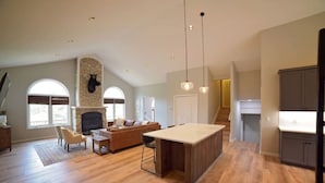 A spacious living area with a fireplace, a large island, and a kitchen with grey cabinets. - Spacious and Scenic Mountain Home (Silverthorne)