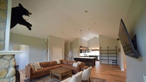 A spacious living area with a large sectional sofa, a coffee table, and a fireplace. There is a kitchen in the background with a bar area. - Spacious and Scenic Mountain Home (Silverthorne)