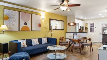 A living room with a blue sofa, a round coffee table, and a ceiling fan.