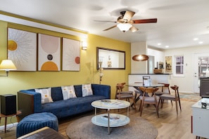 A living room with a blue sofa, a round coffee table, and a ceiling fan. - Outpost: Pitchfork 452 - Close to Snow King Mtn! (Jackson)
