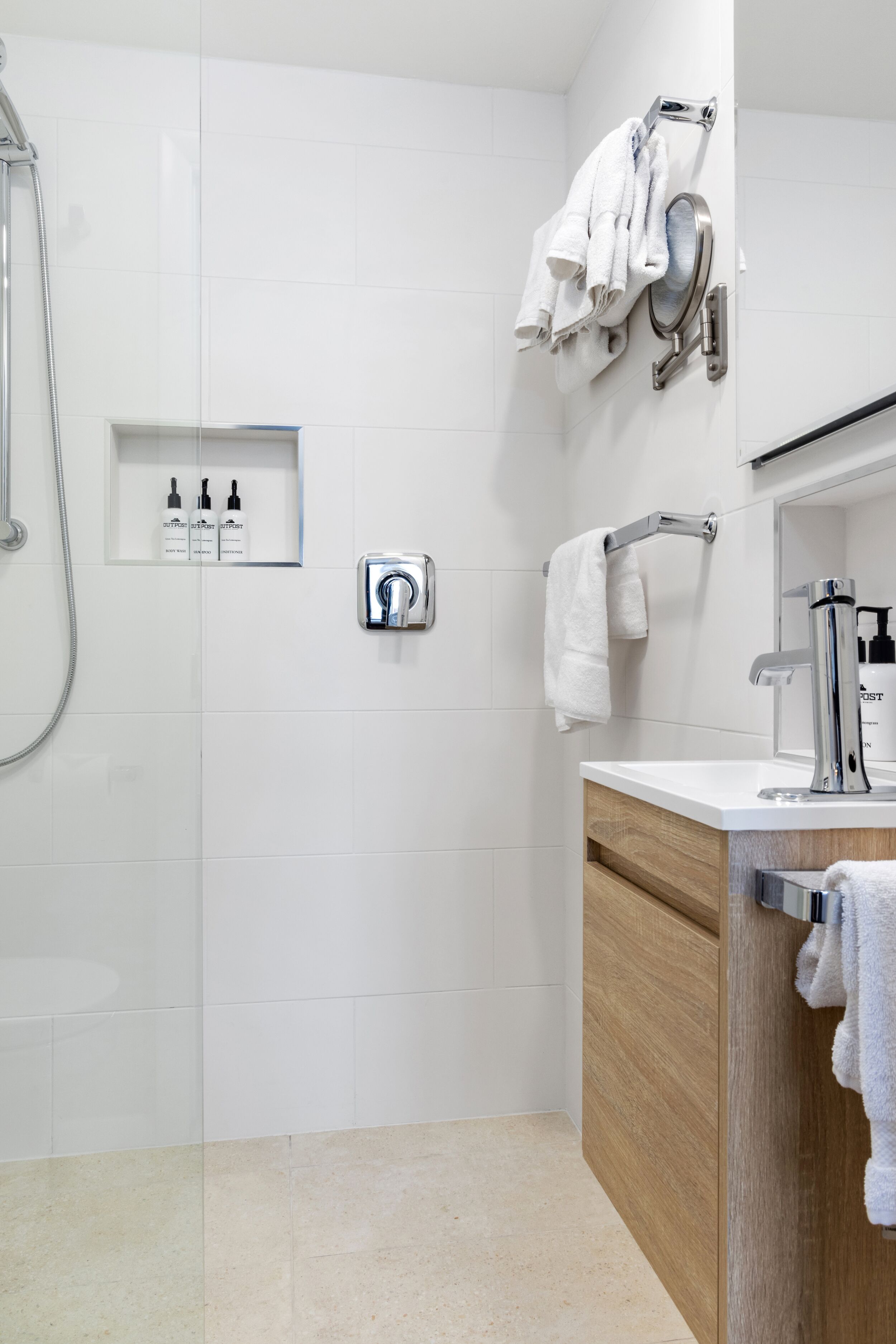Un bany modern amb dutxa, un lavabo amb mirall i un suport per a tovalloles.