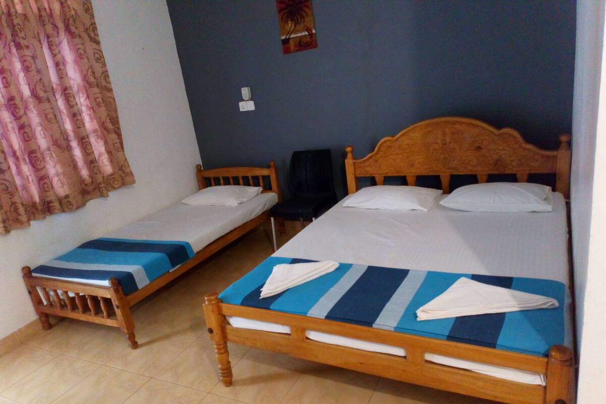 A room with two wooden beds, each with a blue and white striped bedspread and white pillows.