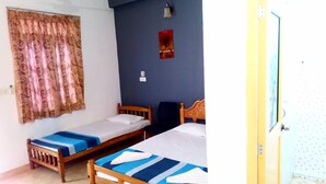 A room with two single beds, a ceiling fan, a wall-mounted light, and a door. - Nilaveli Hotel Onethra (Trincomalee)