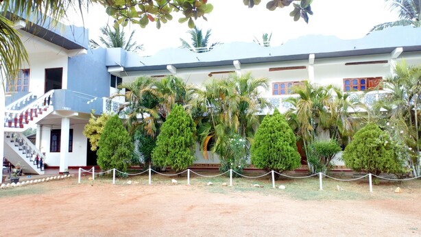 A building with a staircase, multiple trees, and a fenced area. - Nilaveli Hotel Onethra (Trincomalee)