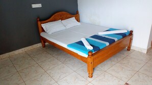 A single bed with a wooden frame, white linens, and a blue and white striped blanket. - Nilaveli Hotel Onethra (Trincomalee)