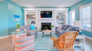 A living room with a fireplace, two sofas, a coffee table, and a television. - Coastal Club * 6BR Luxury House (Lewes)