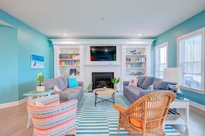 A living room with a fireplace, two sofas, a coffee table, and a television.