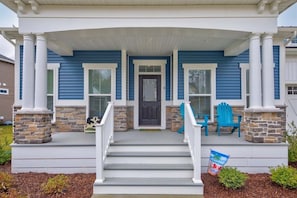 A house with a porch, a front door, and two blue chairs.