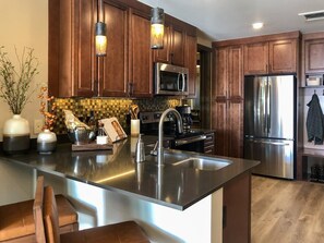 Enjoy cooking in this well-equipped kitchen with a large island, range hood, stainless steel appliances, and a mosaic backsplash.