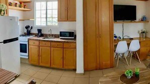 Una cucina compatta con mobili in legno, un forno a microonde e un'area pranzo con tavolo e sedie.