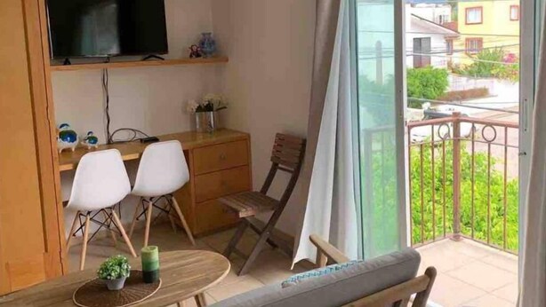 Un balcone con zona pranzo, un televisore su uno scaffale e vista sul quartiere.