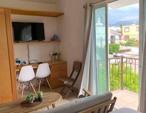 A balcony with a dining area, a TV on a shelf, and a view of the neighborhood.