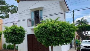 Una casa a due piani con una porta marrone e un balcone.