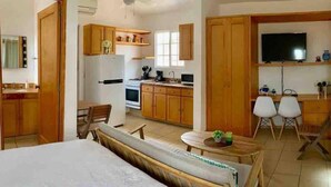 Una stanza con un letto, un tavolo da pranzo, un angolo cottura e una TV.