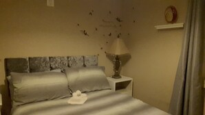 Un lit bien fait, avec des oreillers, une table de chevet avec une lampe et un porte-serviettes avec des serviettes.