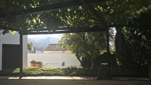 A covered outdoor area with a view of a building, potted plants, and a wooden bench. - House with garden and views in a natural area 15' from the bustling city center (Granada)