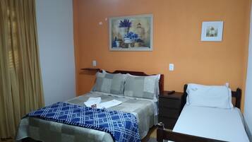 Quarto com cama, mesa de cabeceira, ventoinha no teto e um quadro na parede.