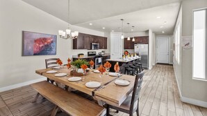 Une cuisine moderne avec des meubles en bois foncé, un îlot central et des luminaires suspendus.