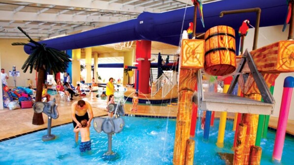Un parc aquatique intérieur comprenant une piscine, des toboggans et des aires de jeux aquatiques.