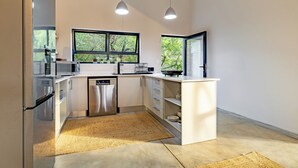 A modern kitchen with white cabinetry, stainless steel appliances, and a large window providing a view of greenery.