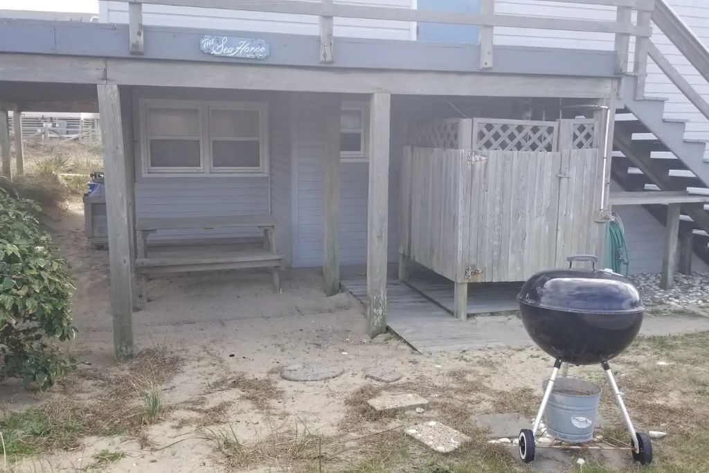 Ein Garten mit einer Holzterrasse, einem Grill und einer Bank.