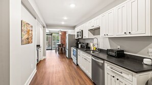 Una cocina moderna con armarios blancos, encimera negra y electrodomésticos de acero inoxidable.