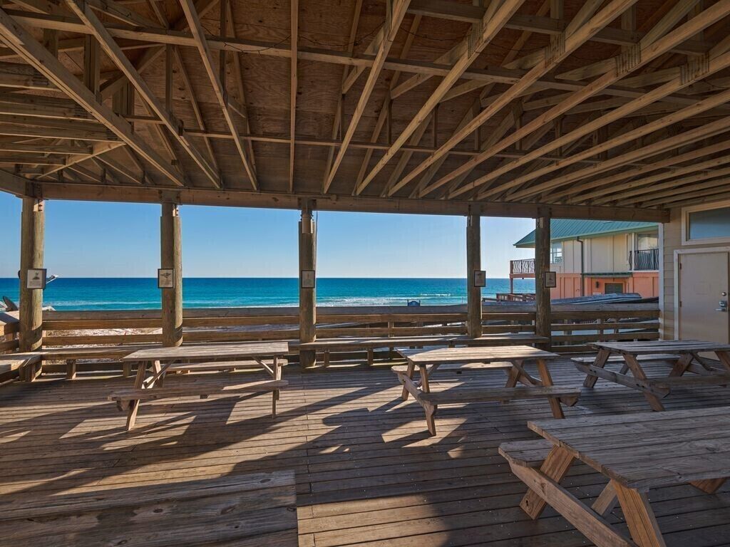 A wooden deck with picnic tables overlooking the ocean.