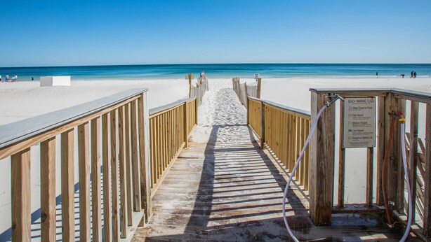 Un muelle de madera que conduce a una playa con agua azul cristalina.