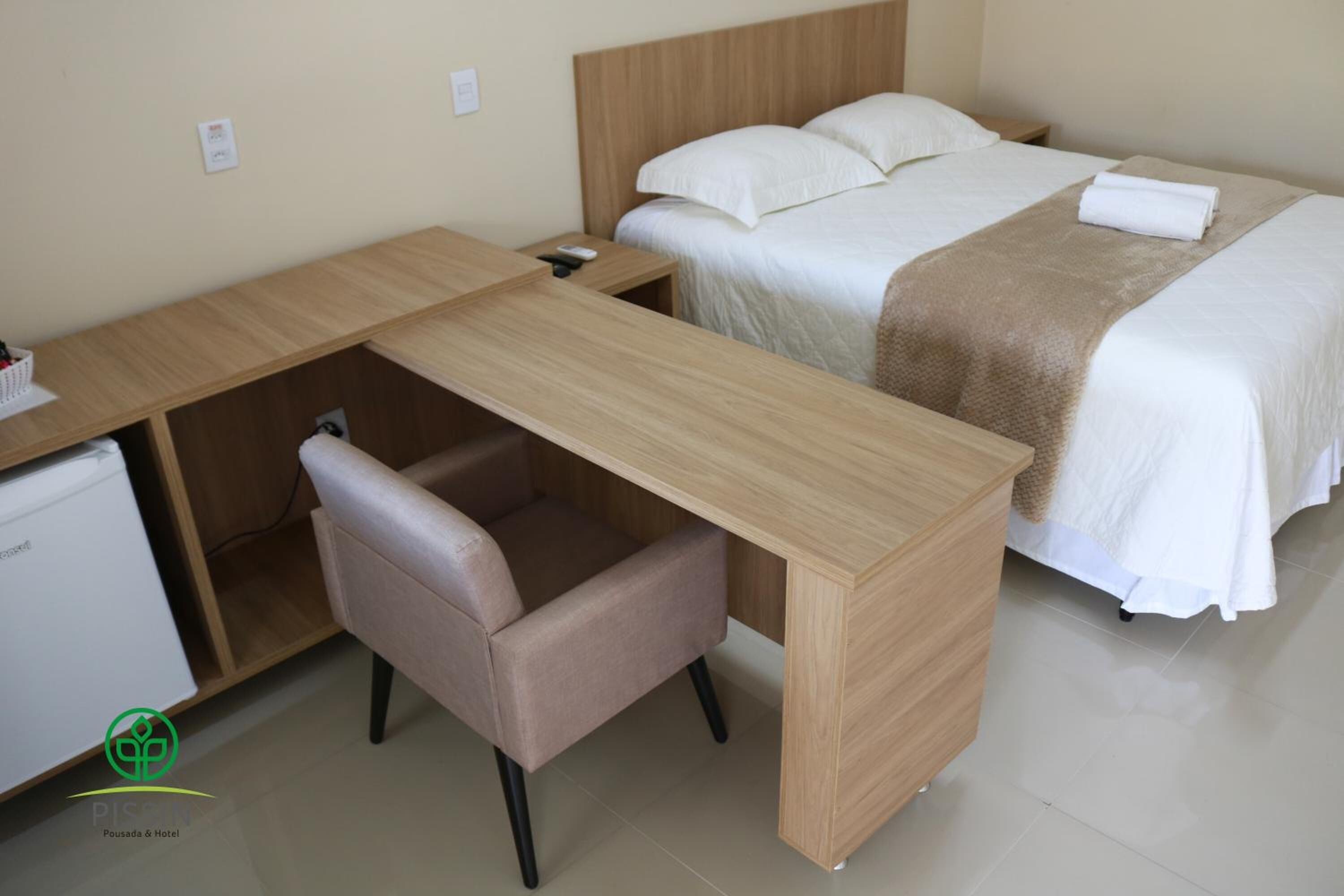 A hotel room with a bed, a desk, and a chair.