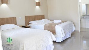 Een hotelkamer met twee bedden, een houten hoofdeinde, een nachtkastje, een wandairco en een badkamer met betegelde wand en aanrecht.