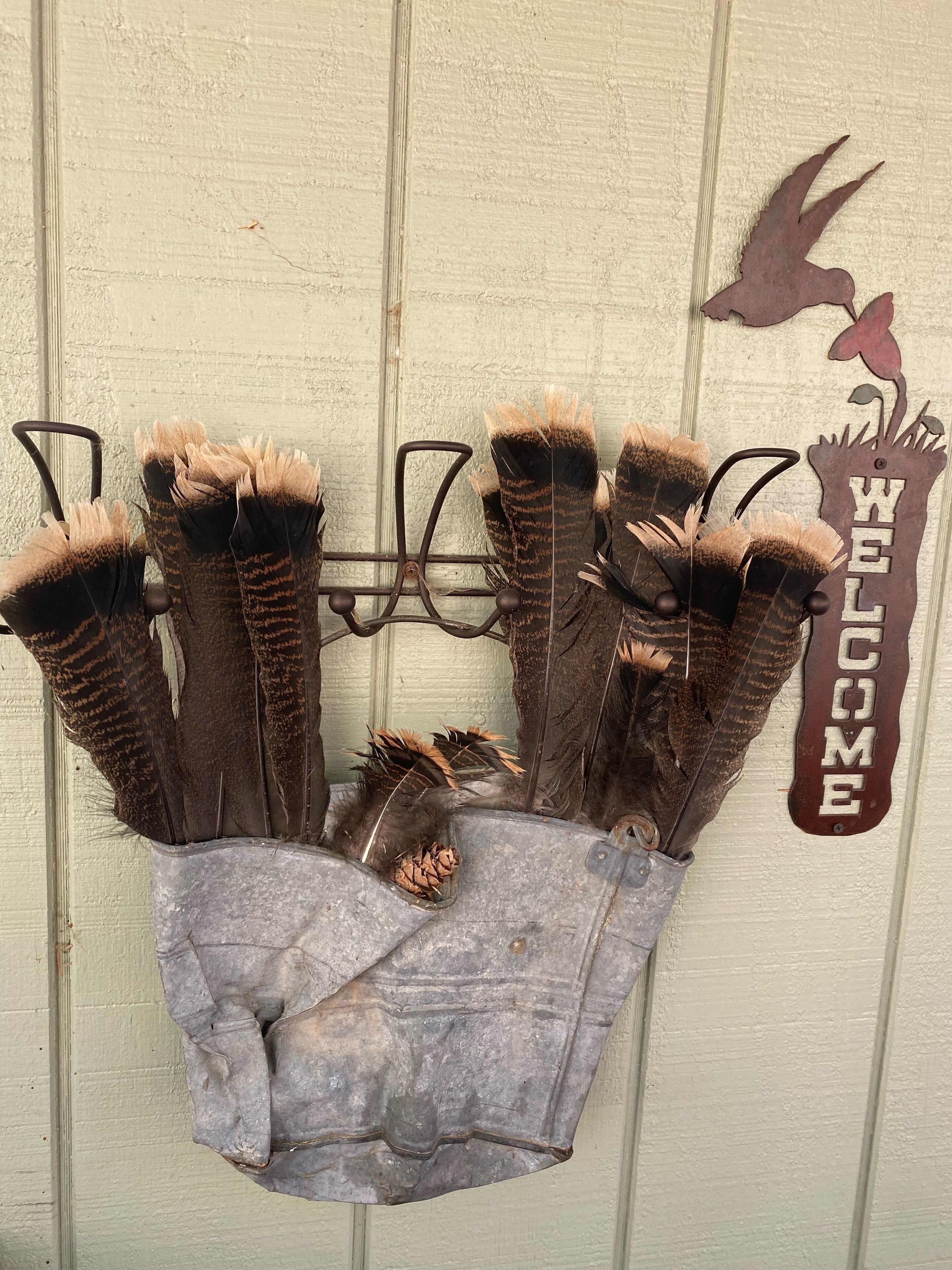 A rustic wall-mounted bird feeder with a 'WELCOME' sign and a bird silhouette.
