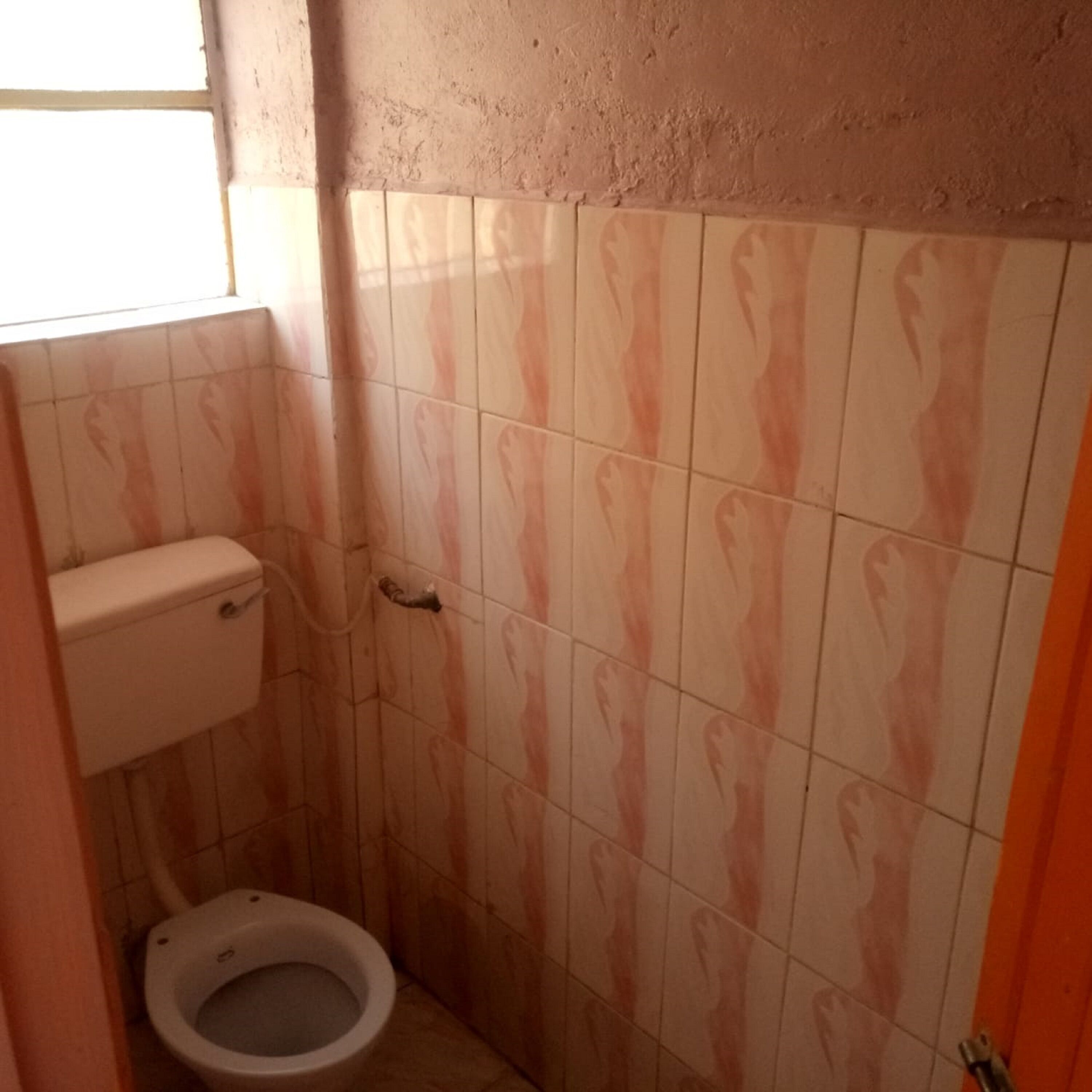 A small bathroom with a toilet, a wall-mounted sink, and a window providing natural light.