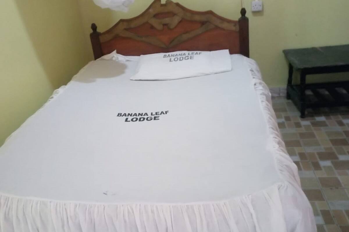 A bed with a white bedspread and a pillow labeled "BANANA LEAF LODGE".