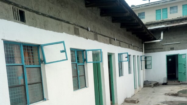 A building with multiple windows and doors, some with green frames, and a concrete floor with visible wear. - California Naivasha Lodge (Naivasha)