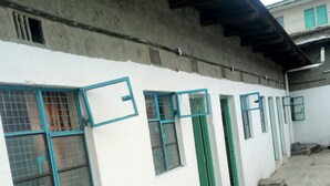 A building with multiple windows and doors, some with metal grilles. - California Naivasha Lodge (Naivasha)