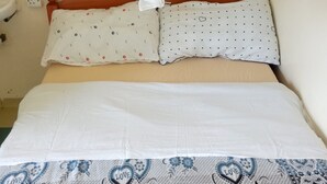 A bed with white bedding and a patterned bedspread featuring hearts and floral designs. - California Naivasha Lodge (Naivasha)