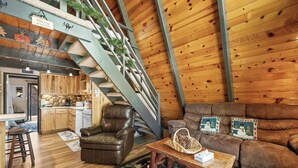 Ein gemütliches Interieur mit einer Holztreppe, einem Ledersessel, einer Couch und einem rustikalen Couchtisch.