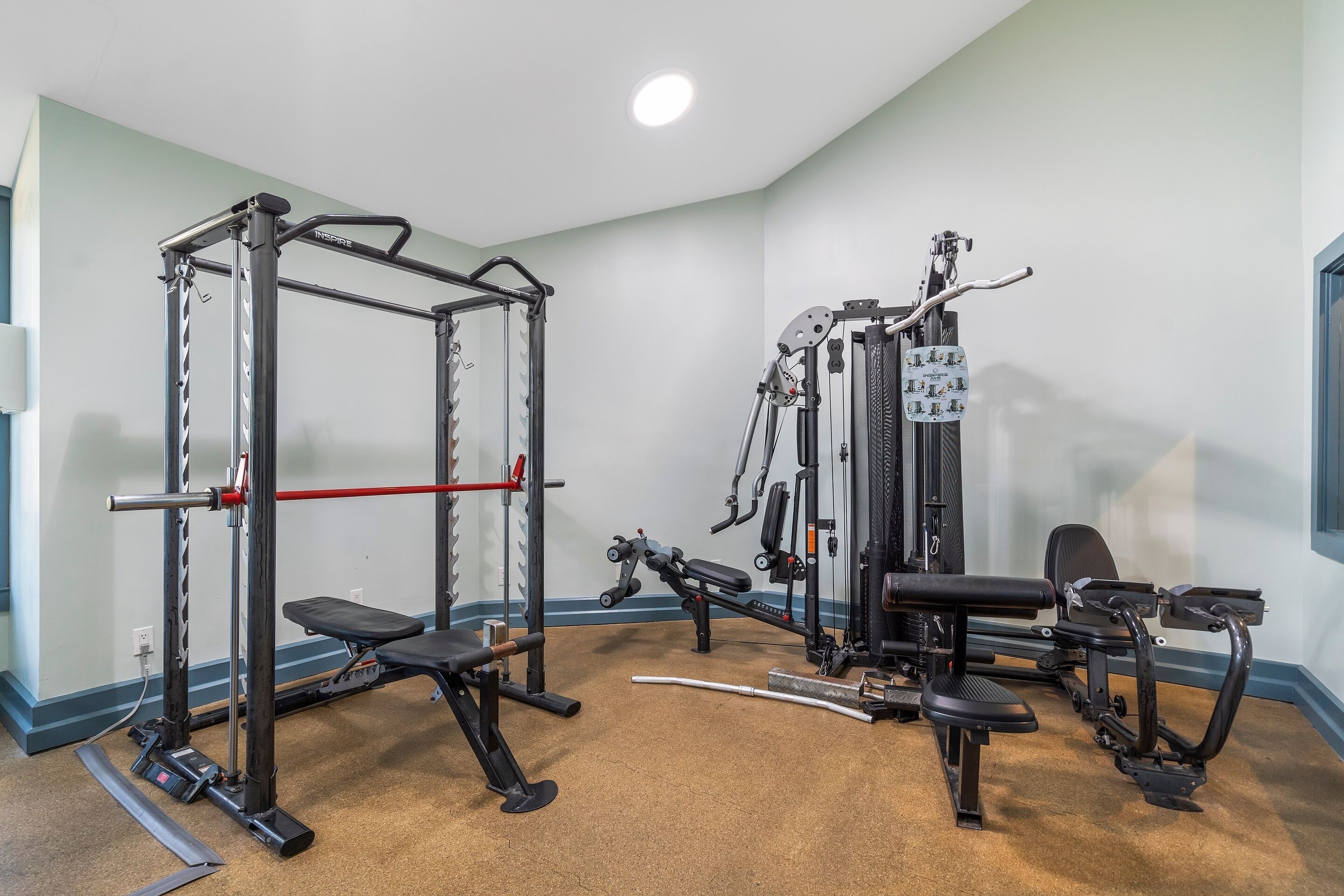 Een sportschool met diverse fitnessapparaten, een bank en een fiets aan de muur.