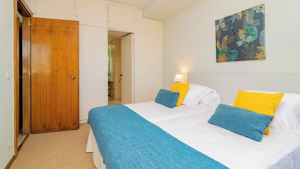 A bedroom with a bed, a wardrobe, and a bathroom visible through an open door.