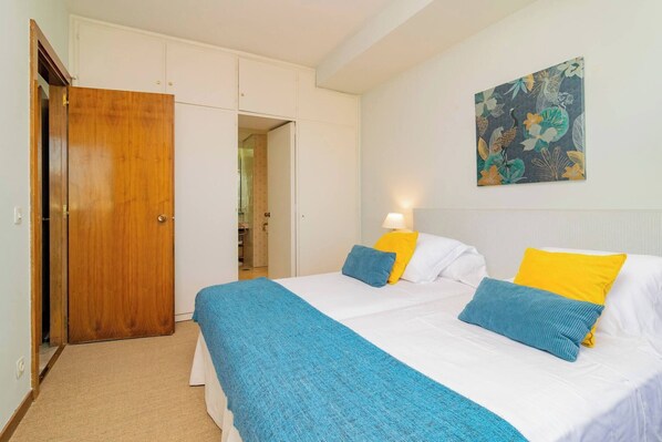 Une chambre à coucher avec un lit, une armoire et une salle de bain visible à travers une porte ouverte.