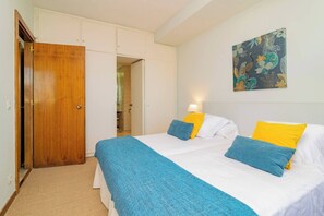 Quarto com cama, porta de madeira, guarda-roupa branco e um quadro na parede.