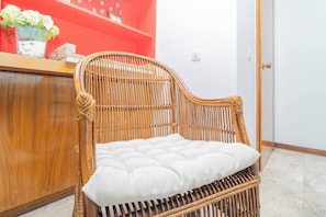 Een rieten stoel met een bekleed zitoppervlak in een kamer met een houten toonbank en een rode plank.