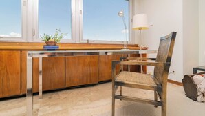 A modern kitchen with wooden cabinets, a glass countertop, and a chair with a woven backrest.