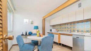 A compact kitchen with a round table, two chairs, a microwave, a sink, and a dishwasher.